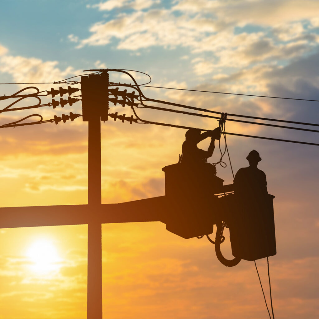 Electricians wearing fall-protection equipment while working at height